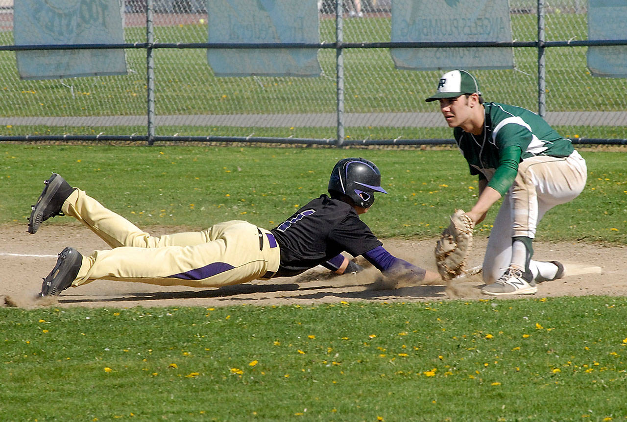 Keith Thorpe/Peninsula Daily News Sequim’s Michael Young dives back to first as Port Angeles first baseman Bo Bradow waits for the ball during the first inning on Wednesday in Sequim.