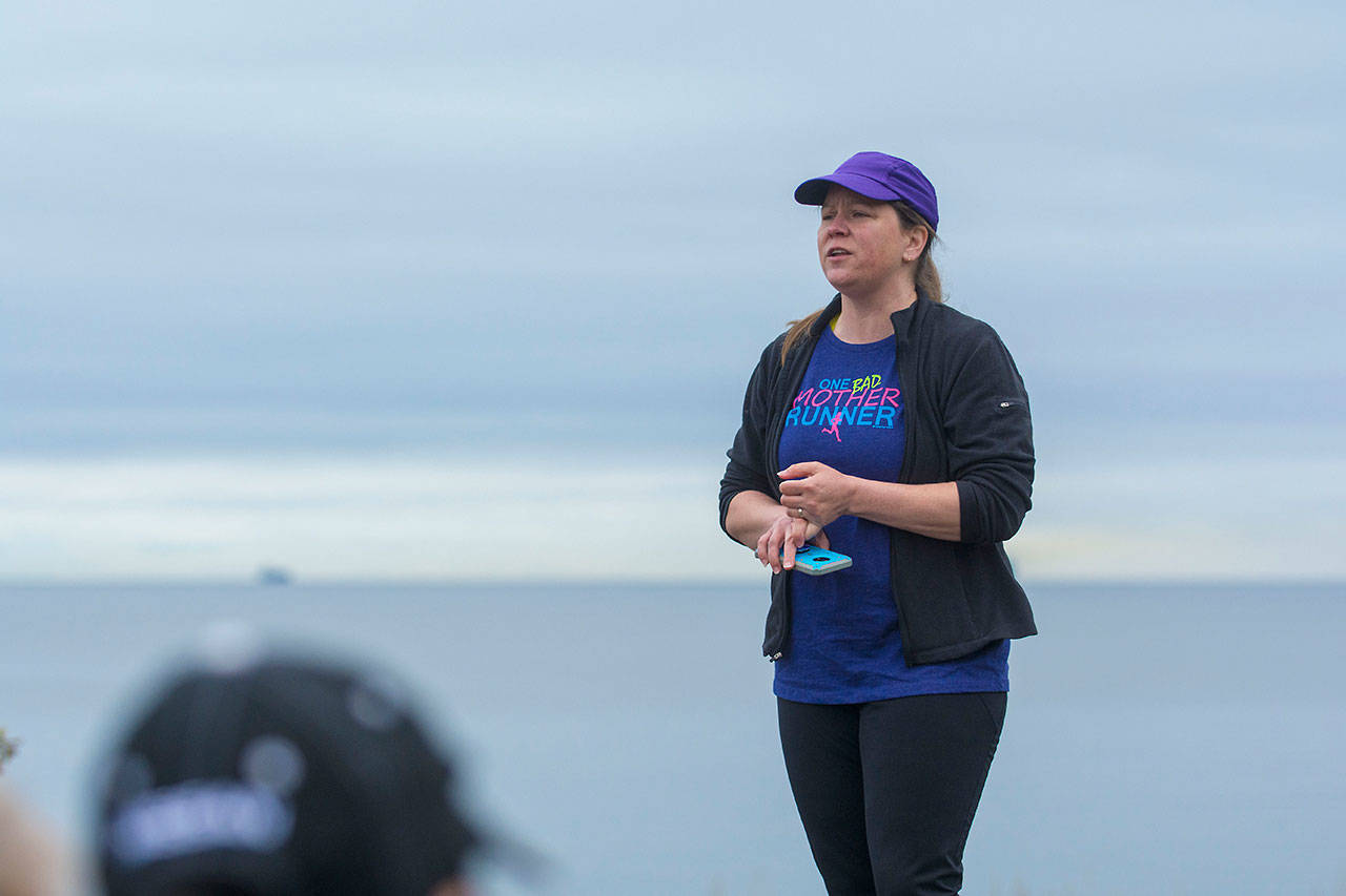 Carrie Sanford, who organized the Run Without Fear, stands atop a table as she tells a group of mostly women that the goal was to “take back” the Olympic Discovery Trail on Sunday. (Jesse Major/Peninsula Daily News)