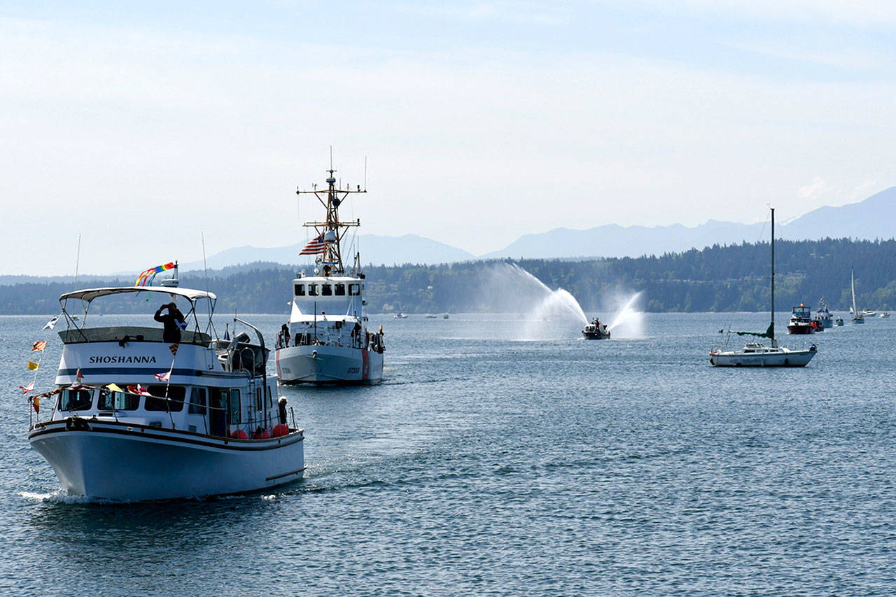 The Shoshanna, a Ralston Trawler owned by Carl and Sue Sidle of the Port Townsend Yacht Club, glides by the reviewing dock at the Northwest Maritime Center during Saturday’s opening day celebration of boating season. It is followed by the Coast Guard Patrol Boat Swordfish and the East Jefferson Fire Rescue boat Guardian, its water cannons sending out a celebratory spray. (Jeannie McMacken/ Peninsula Daily News)