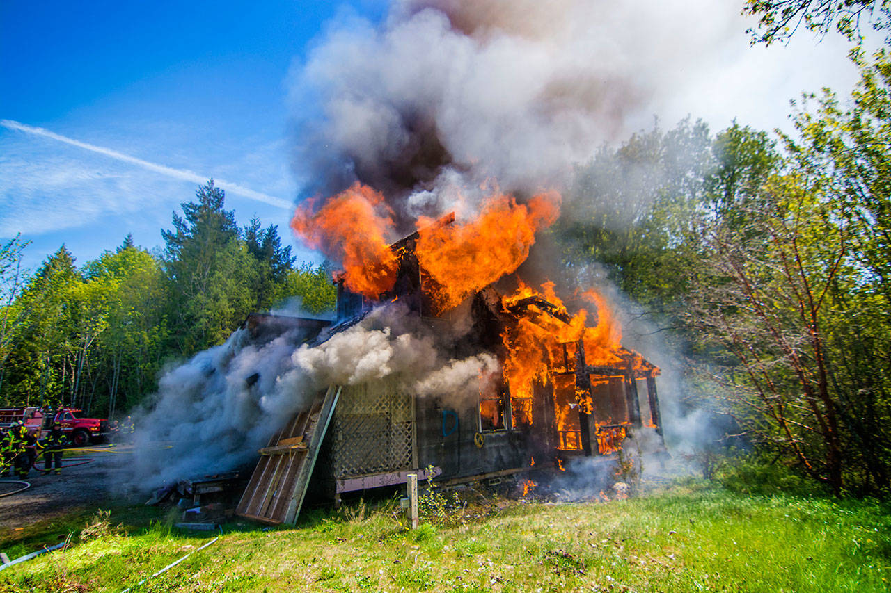 A home on Garling Road used for fire training burns on Saturday. (Jesse Major/Peninsula Daily News)
