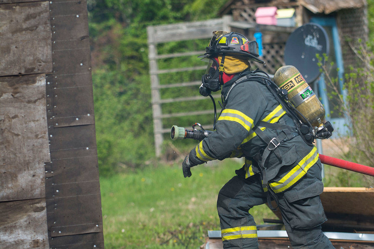 A firefighter leads the attack as he enters a house on Garling Road near Port Angeles during fire training Saturday. (Jesse Major/Peninsula Daily News)