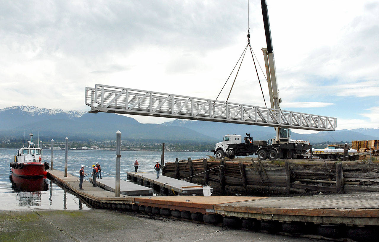 A mobile crane lifts an 80-foot gangway onto sections of floating dock before it is floated from Ediz Hook to Port Angeles City Pier on Tuesday. (Keith Thorpe/Peninsula Daily News)