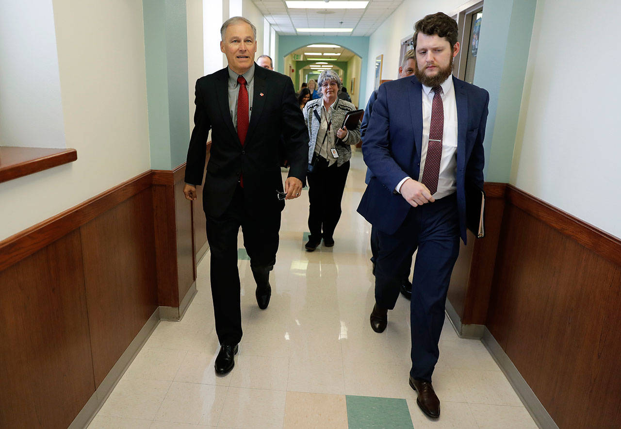 Gov. Jay Inslee, left, walks through a hallway inside Western State Hospital with Cheryl Strange, center, CEO of Western State Hospital, and David Westbrook, right, the Governor’s Director of Outreach, on Friday following a meeting with the hospital’s executive team in Lakewood. (Ted S. Warren/The Associated Press)