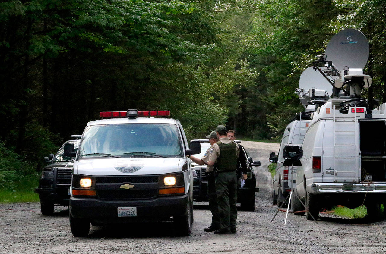 State Fish and Wildlife Police confer with an individual from the King County Medical Examiner’s office on a remote gravel road above Snoqualmie following a fatal cougar attack Saturday. (Alan Berner/The Seattle Times via AP)