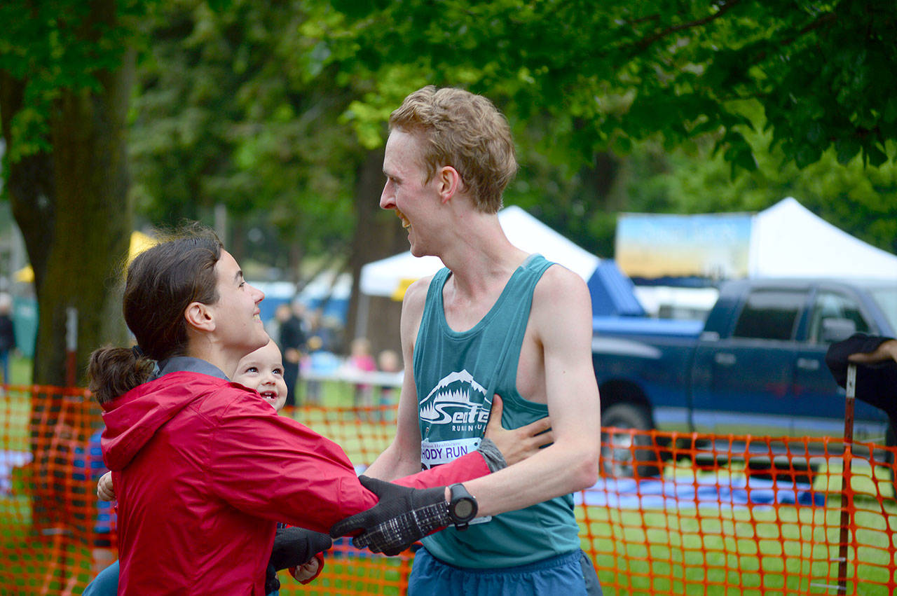 Winner Keith Laverty greets his wife Elisa and son Luke after crossing the finish line in Sunday’s Rhody Run. (Diane Urbani de la Paz/for Peninsula Daily News)