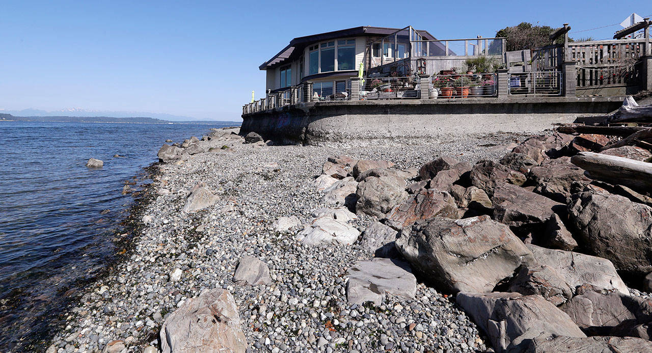 A house fronted with a concrete seawall along the Puget Sound stands adjacent to a more natural area of beach, boulders and logs, Tuesday in Seattle. (Elaine Thompson/The Associated Press)