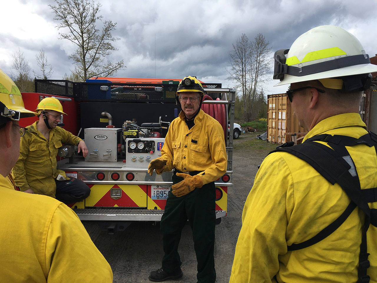 Clallam County Fire District No. 2 Lt. Al Oman, facing the crews, explains the safe operation of pumps on a new brush engine as firefighters look on. (Clallam County Fire District No. 2)