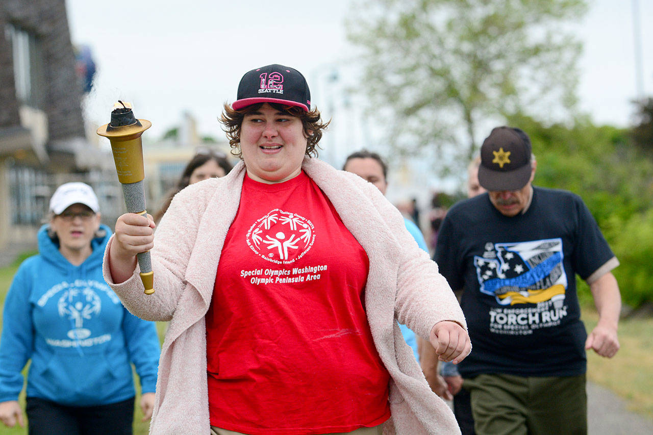 Bonny Cates of Port Angeles carries a torch on the Olympic Discovery Trail on the Port Angeles Waterfront during the 2017 Law Enforcement Torch Run. (Jesse Major/Peninsula Daily News)