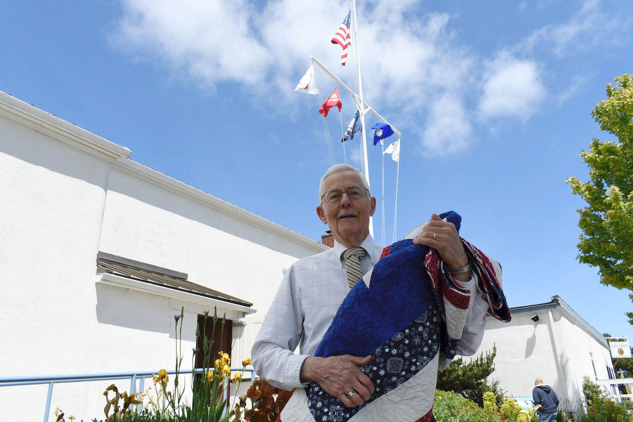 Army veteran Walter Vaux displays his Quilt of Valor, handmade by local members of the Quilts of Valor Foundation. The group presented 21 quilts at the Memorial Day ceremony at the Marvin G. Shields Memorial Post No. 26 in Port Townsend. (Jeannie McMacken/Peninsula Daily News)