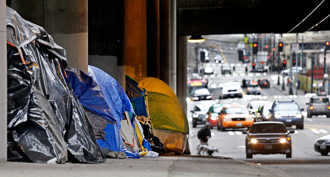 Tarp-covered tents line a sidewalk beneath a highway and adjacent to downtown Seattle on March 8. Seattle Mayor Jenny Durkan wants to move hundreds more homeless people into tiny homes, emergency shelters and other immediate housing in the next 90 days. (Elaine Thompson/The Associated Press)