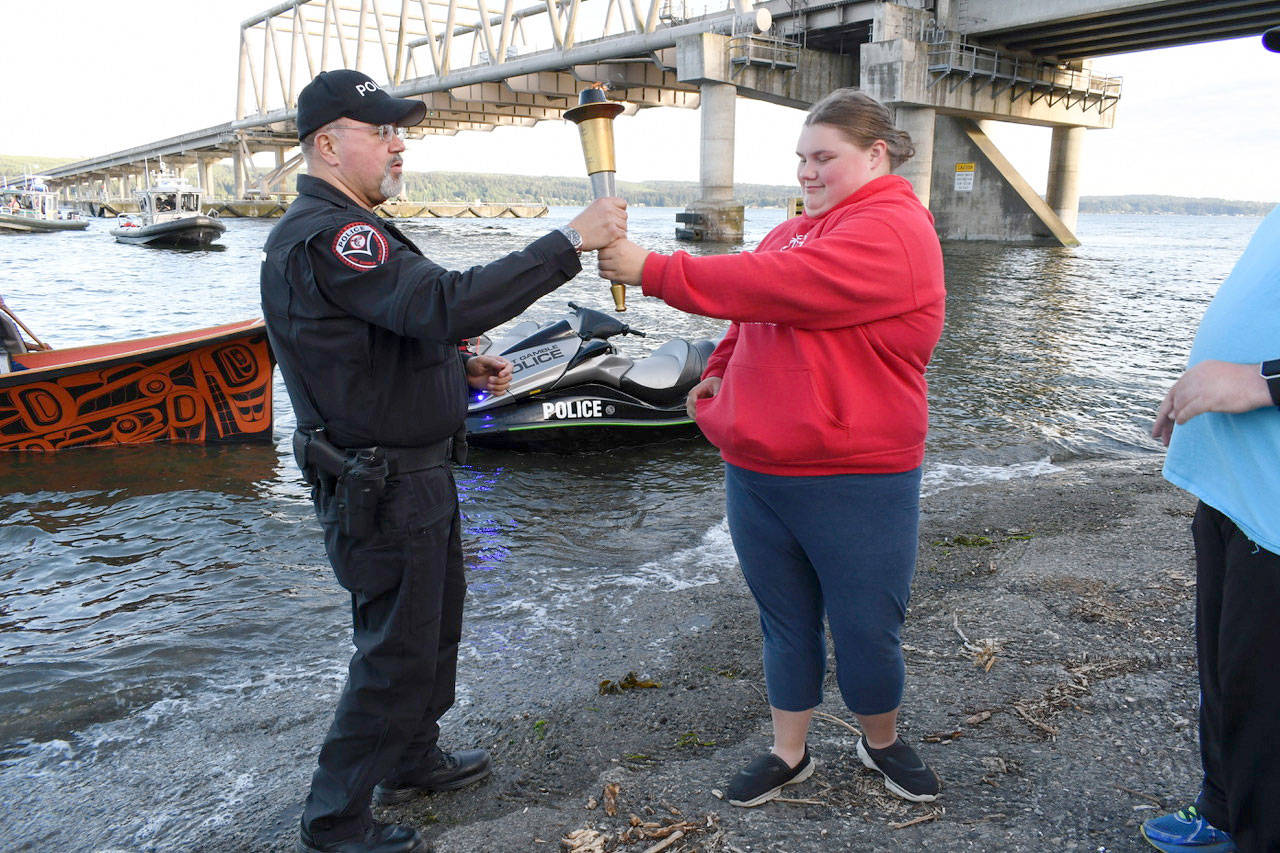 Special Olympian Kaylee Krajewski hands off the torch to a member of the Port Gamble SKlallam tribal police Wednesday to mark the end of the Jefferson County leg of the Special Olympics Torch Run. The Jefferson County Sheriffs Office, Port Townsend Police Department, Special Olympians and athletes from Port Townsend High School ran the 15-mile leg of the event that will conclude in Pacific Lutheran University in Tacoma today. The run began near Port Angeles at 7 a.m. (Jeannie McMacken/Peninsula Daily News)