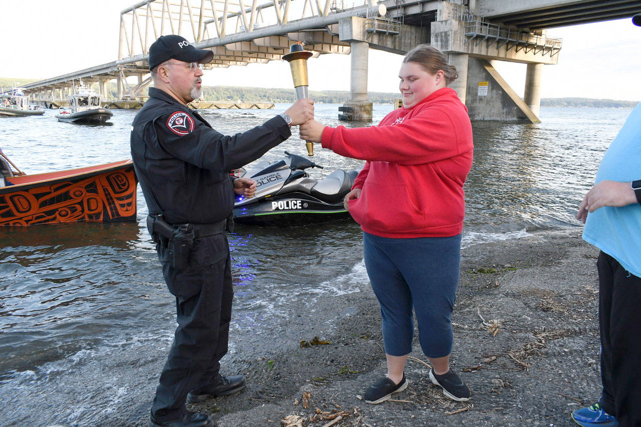 Special Olympian Kaylee Krajewski hands off the torch to a member of the Port Gamble S’Klallam tribal police Wednesday to mark the end of the Jefferson County leg of the Special Olympics Torch Run. The Jefferson County Sheriff’s Office, Port Townsend Police Department, Special Olympians and athletes from Port Townsend High School ran the 15-mile leg of the event that will conclude in Pacific Lutheran University in Tacoma today. The run began near Port Angeles at 7 a.m. (Jeannie McMacken/Peninsula Daily News)