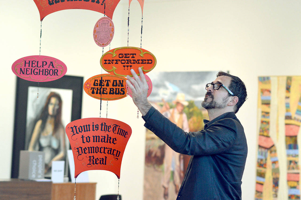Michael D’Alessandro of the Northwind Arts Center interacts with “The Gentle Revolution,” a mobile made by Remedios Rapoport. (Diane Urbani de la Paz/for Peninsula Daily News)