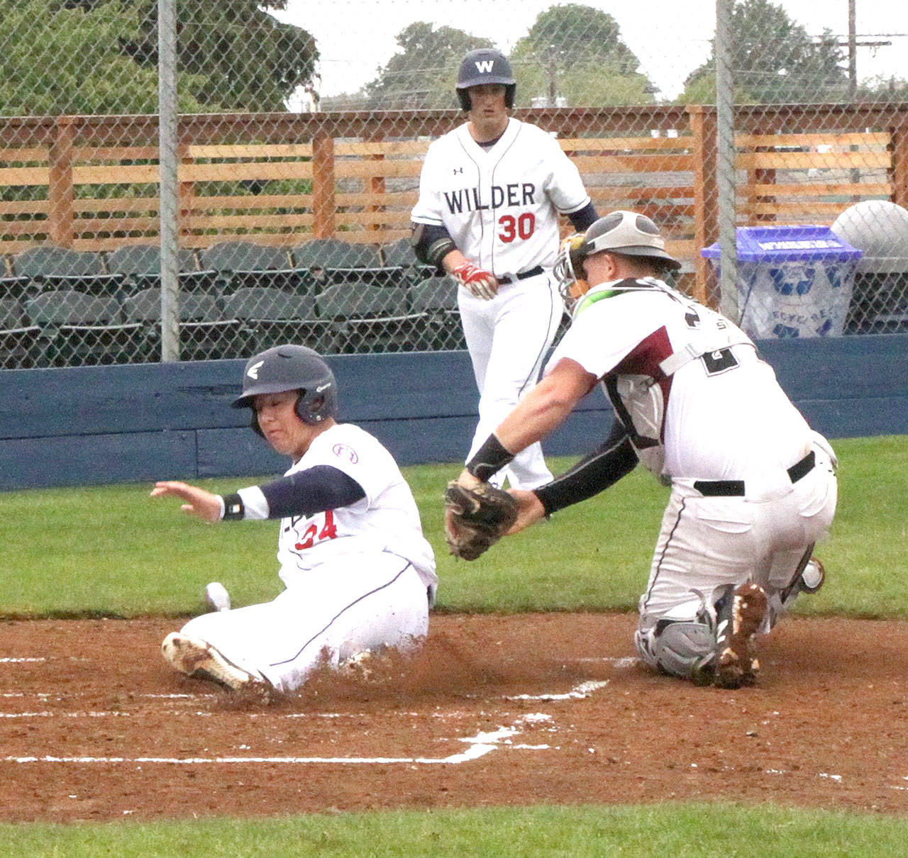 Wilder third baseman Johnnie Young is called out as he slides into home as he is tagged by NW Blaze’s Woch Wiseman. No. 30 is Wilder’s Brody Merritt. (Dave Logan/for Peninsula Daily News)