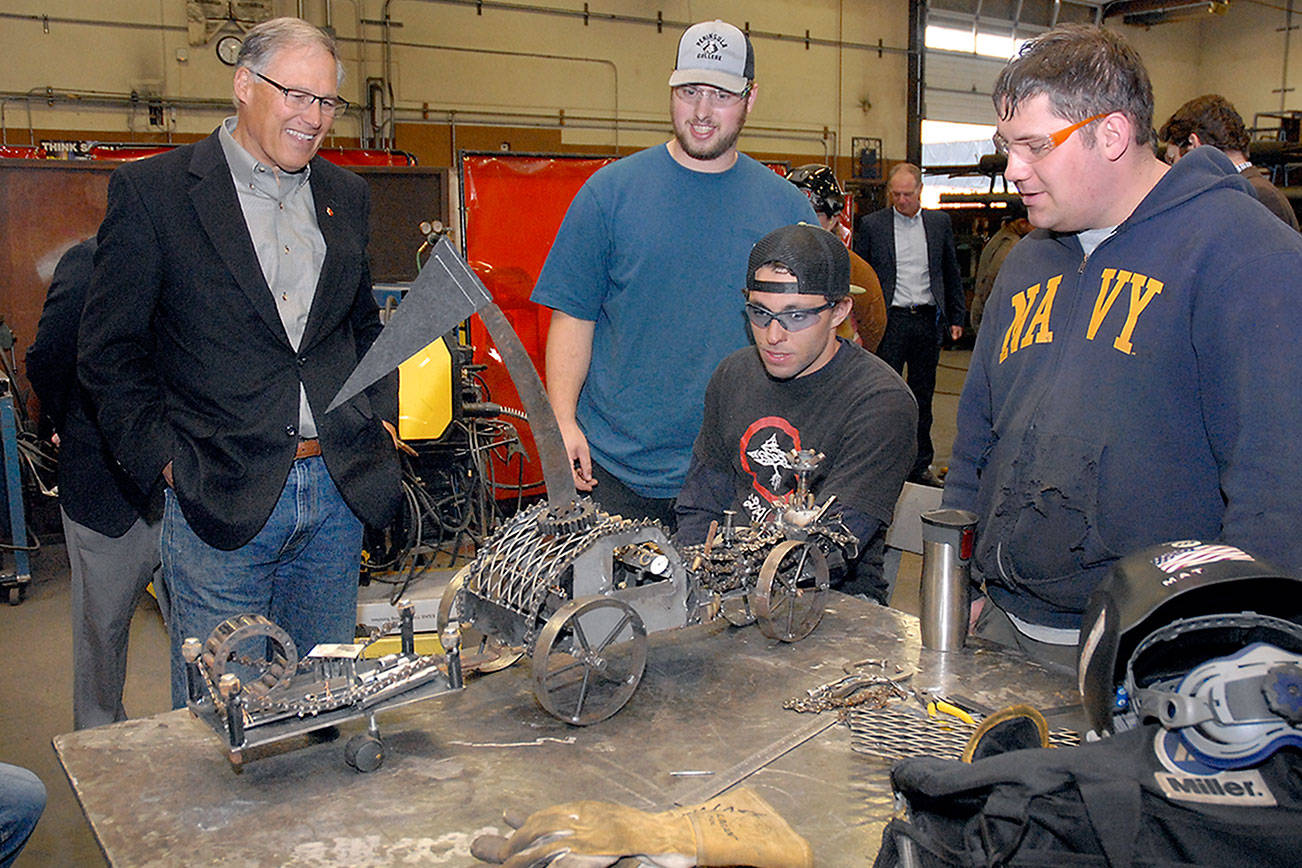 Keith Thorpe/Peninsula Daily News Washington Gov. Jay Inslee, left, examines a steampunk-themed metal artwork created by Peninsula College welding students, from left, Ellis Henderson of Port Townsend, and Nathan Hofer and Matthew Weaver of Port Angeles during the governor’s tour of the college’s welding class on the Port Angeles campus on Thursday. The shop tour was part of a presentation on economic opportunities and partnerships in the maritime industries on the North Olympic Peninsula.