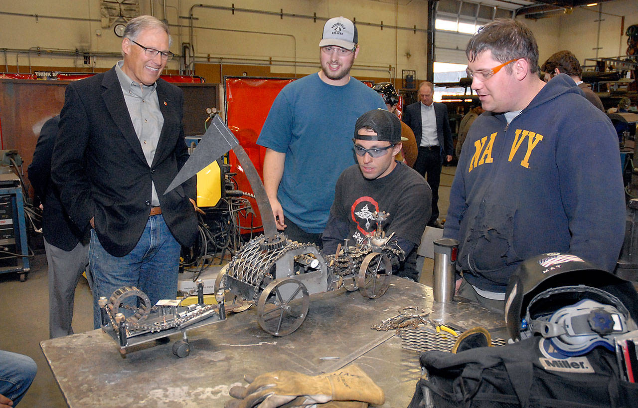 Washington Gov. Jay Inslee, left, examines a steampunk-themed metal artwork created by Peninsula College welding students, from left, Ellis Henderson of Port Townsend, and Nathan Hofer and Matthew Weaver of Port Angeles during the governor’s tour of the college’s welding class on the Port Angeles campus on Thursday. The shop tour was part of a presentation on economic opportunities and partnerships in the maritime industries on the North Olympic Peninsula. (Keith Thorpe/Peninsula Daily News)