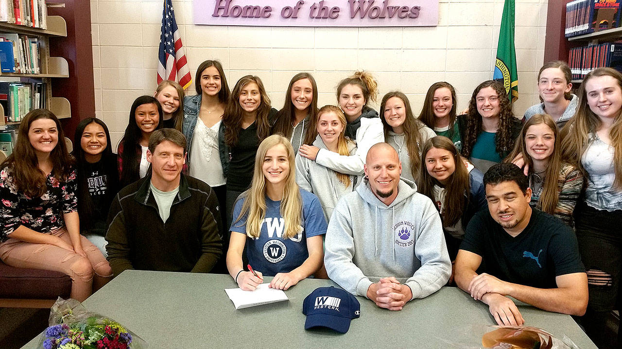 Sequim High School goalkeeper Claire Henninger signs a letter of intent to play soccer at Western Washington University on Wednesday. Henninger was a first-team all-Olympic League 2A three times, was the 2016 Peninsula Daily News All-Peninsula MVP in girls’ soccer. With her during the signing ceremony are her high school coaches, from left, Keith McMinn, Derek Vandervelde and Antonio Frutos and a number of her Wolves’ teammates.