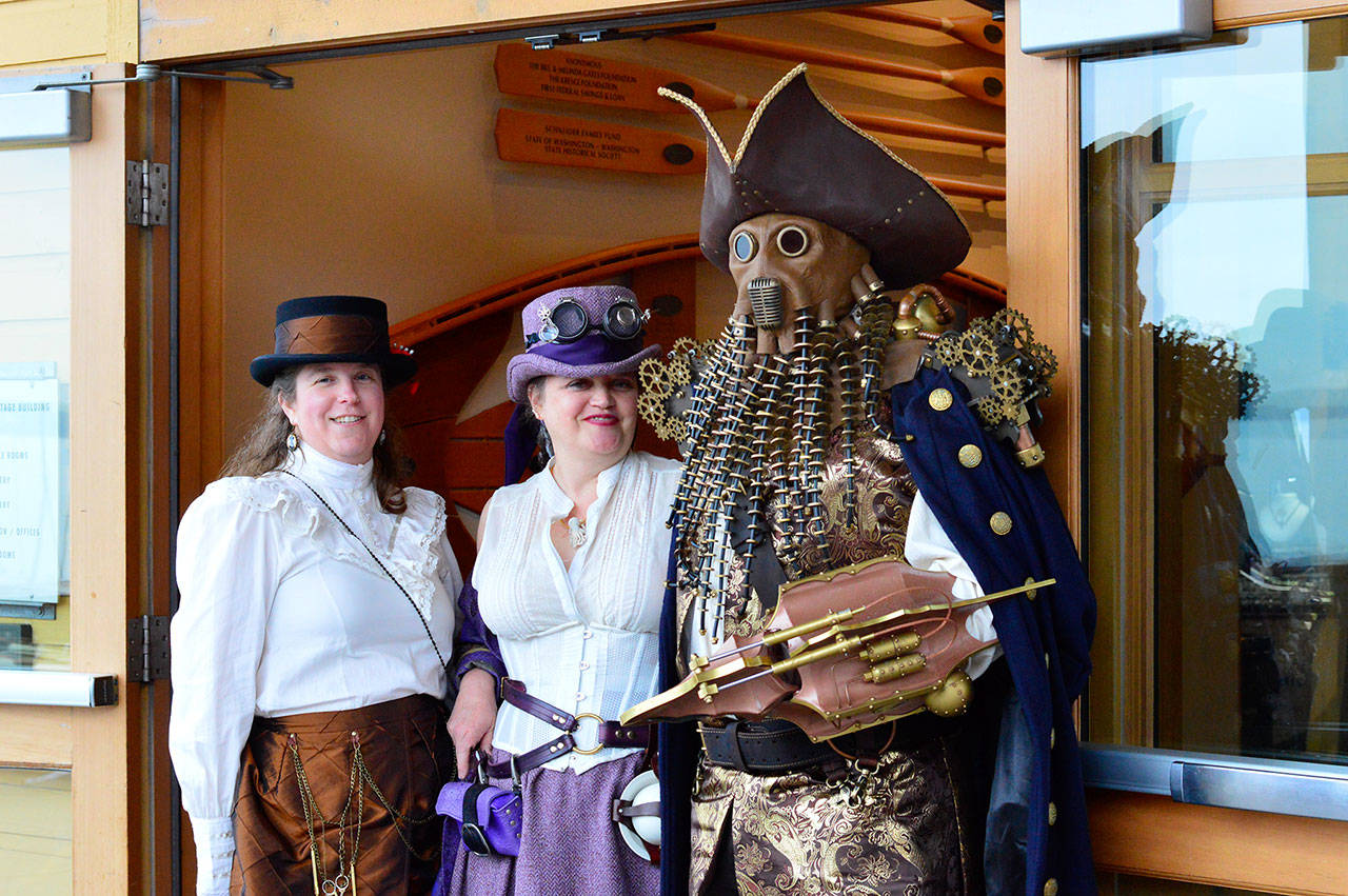 Kelly Wilbur, left, of Arlington, and her husband Tim Wilbur, disguised at right, ran into Koralee Putnam of Pacific at the Bazaar of the Bizarre on Friday evening. The Bazaar, at the Northwest Maritime Center in Port Townsend, is part of the Steampunk Festival happening through today around downtown Port Townsend. (Diane Urbani de la Paz/for Peninsula Daily News)