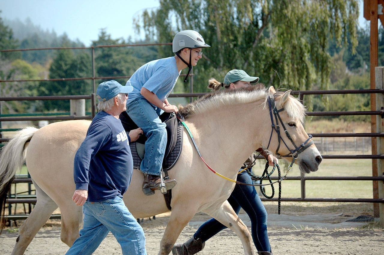 Gabriel Hernandez, 14, of Seattle rides Tikki while volunteers Glenn Reedy, foreground, and Cat Grindall stick close by. (Candace Raab)