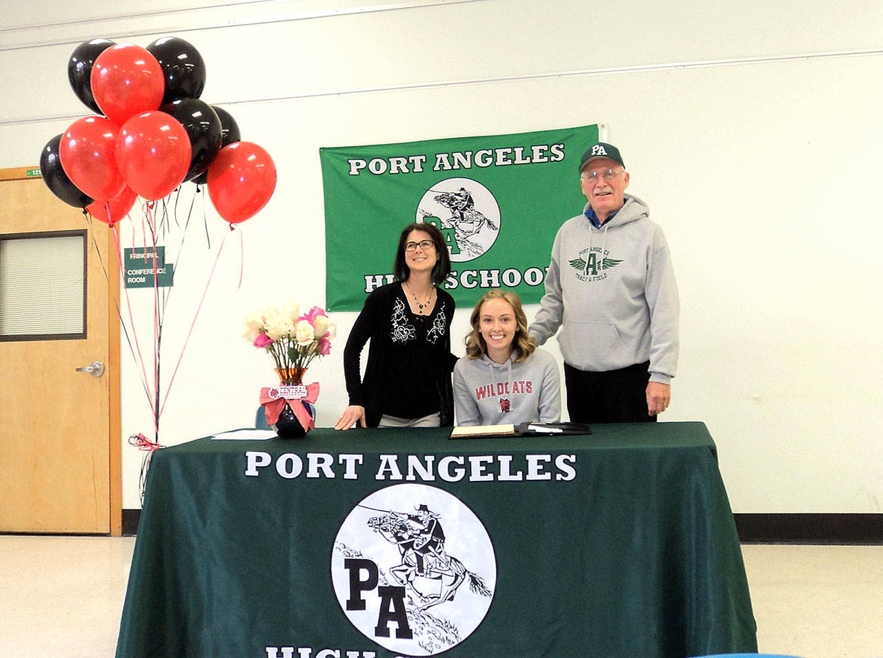 Maddie Dougherty, flanked by her cross-country coach Cheryl Gerardi, left and track coach Bob Sheedy, signs her letter of intent to run track for Central Washington University. (Pierre LaBossiere/Peninsula Daily News)
