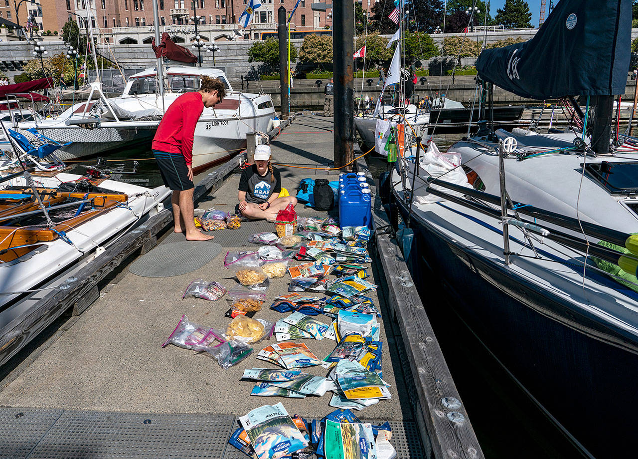 Grant Gridley and Maisie Bryant, two of the five-person crew of Team Blue Flash, inventory the food and water they will be taking with them as they sail to Ketchikan, Alaska, on the second leg of the 750-mile Race to Alaska. (Steve Mullensky/for Peninsula Daily News)