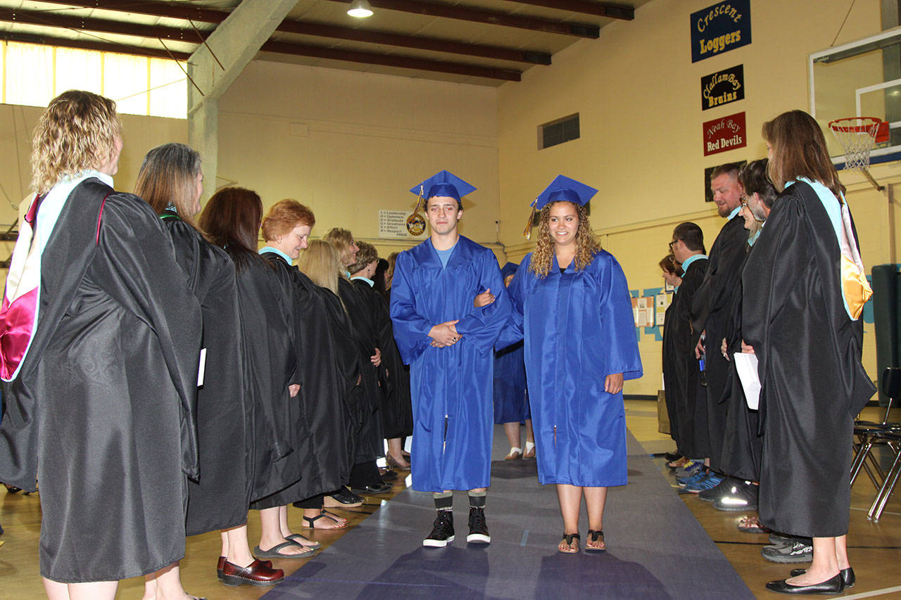 The 15 graduates of Crescent High School march into the gym Saturday with the familiar music of Pomp and Circumstance. Leading the parade through a smiling gauntlet of Crescent school teachers are seniors salutatorian Kyle Buchanan and valedictorian Cecily Clark. (Dave Logan/for Peninsula Daily News)