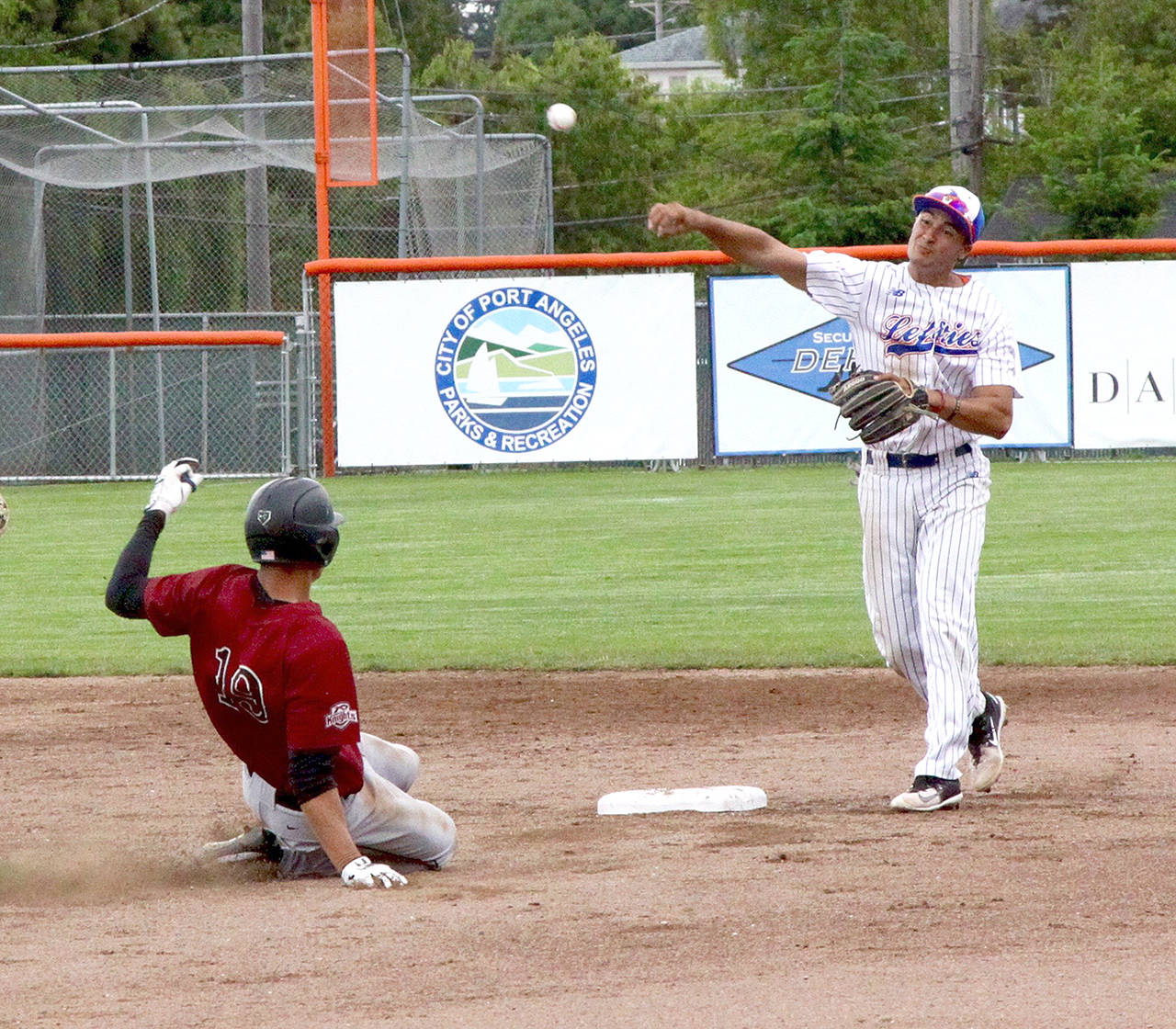 Dave Logan/for Peninsula Daily News Port Angeles’ Jason Dicochea makes a throw to first base to complete a double play after forcing Corvallis’ Cameron Haskell at second Wednesday at Civic Field.