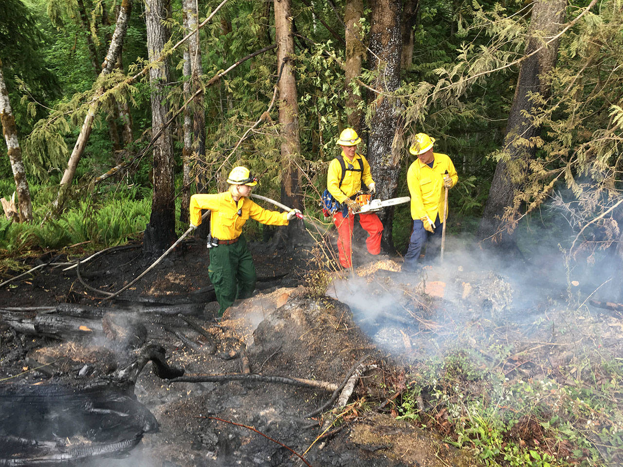 Firefighters Sarah Springob, from left, Tyler Gear and Zach Gear mop up a fire Sunday evening on state Department of Natural Resources land west of Port Angeles. (Clallam County Fire District No. 2)