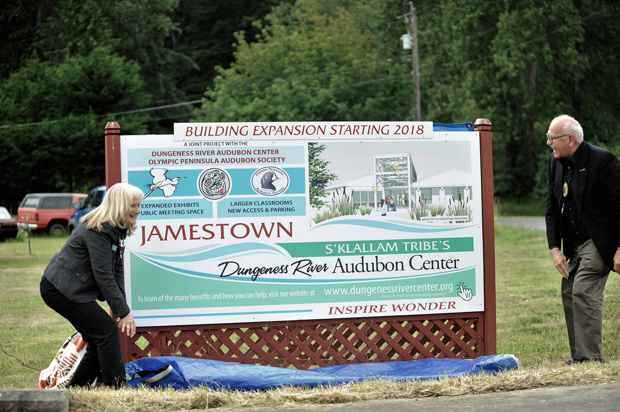 Annette Hanson, capital campaign committee chair for the expansion of the Dungeness River Audubon Center, and Ron Allen, tribal chairman of the Jamestown SKlallam Tribe, reveal a new sign at the entrance to the Railroad Bridge Park. (Matthew Nash/Olympic Peninsula News Group)