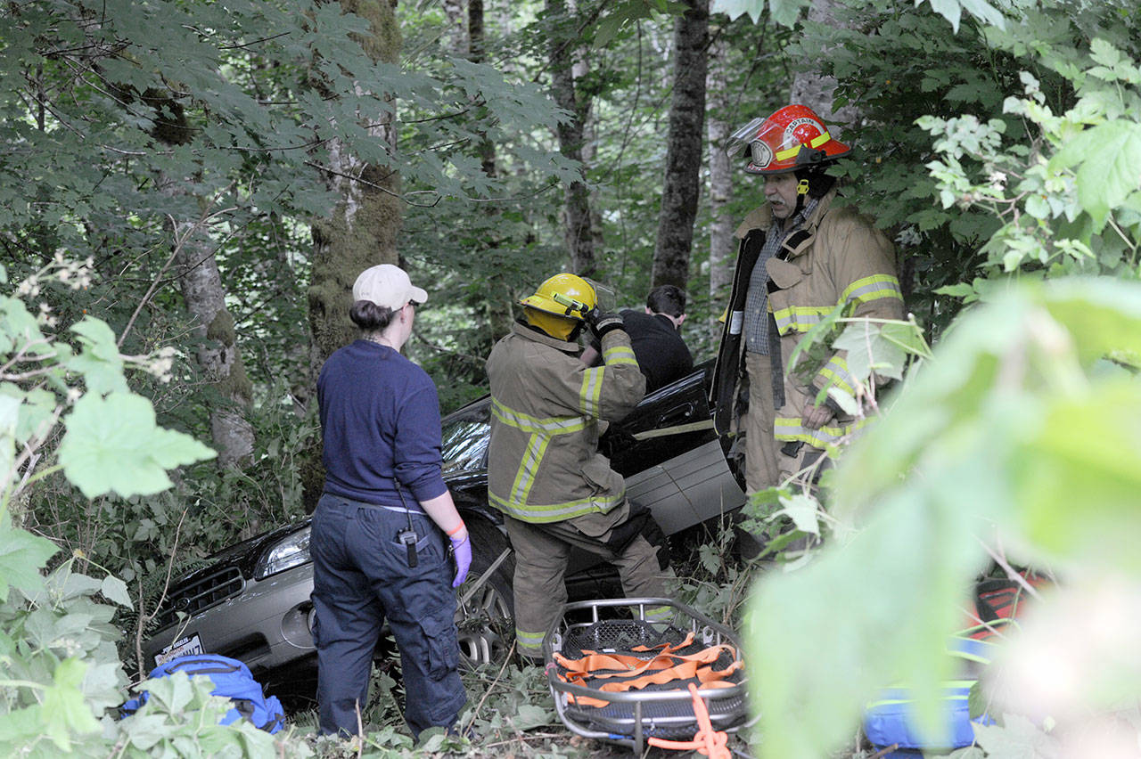 Forks and Beaver fire department personnel and Forks medics prepare to move the wreck victim from his vehicle. He was transported to Forks Community Hospital. (Lonnie Archibald/for Peninsula Daily News)
