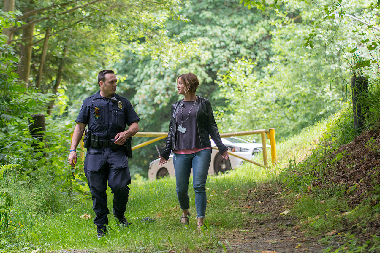 Port Angeles Policer Officer Eric Walker walks with Amy Miller of Volunteers In Medicine of the Olympics as they look for people who may benefit by being connected to services. (Jesse Major/Peninsula Daily News)