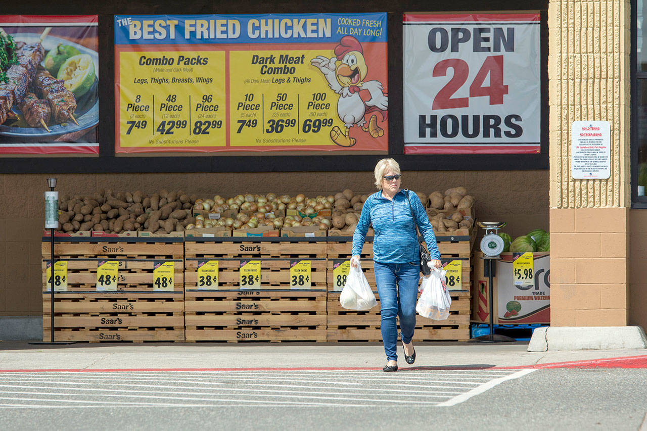 A customer carries groceries out of Saar’s Super Saver Foods on Tuesday. The store is one of several that have been granted temporary exemptions from the city’s ban on plastic bags. (Jesse Major/Peninsula Daily News)