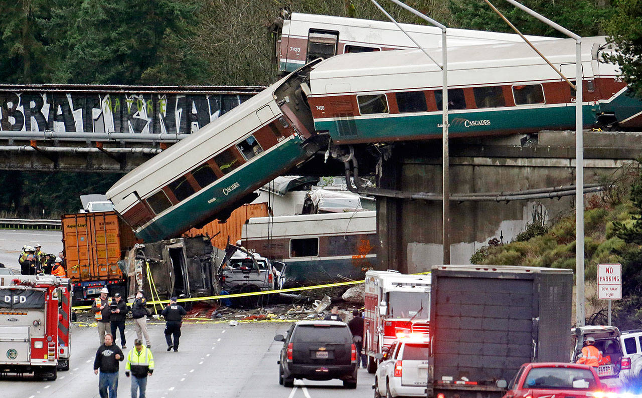 In this Dec. 18, 2017, file photo, cars from an Amtrak train lie spilled onto Interstate 5 below alongside smashed vehicles as some train cars remain on the tracks in DuPont. (Elaine Thompson/The Associated Press)