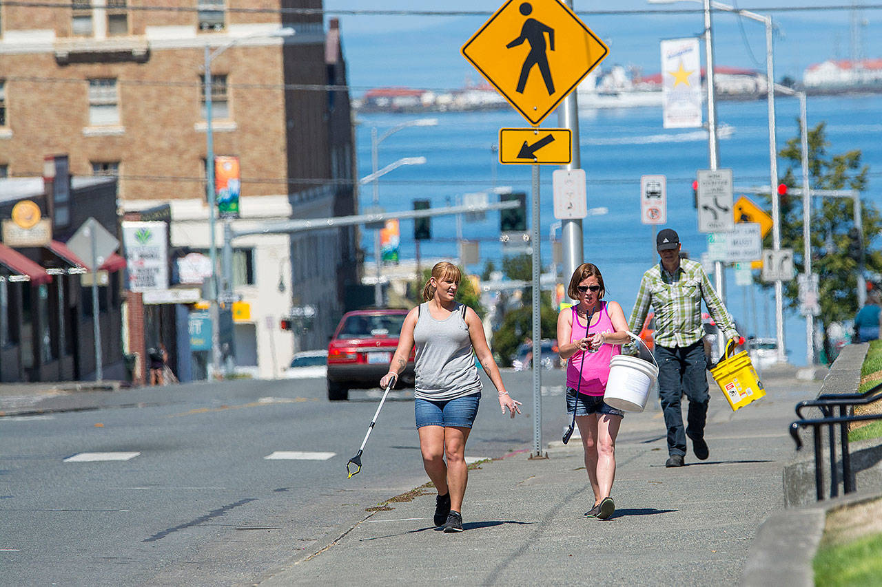 From left, Reagan Mead, Brianna Kelly and Ron Breitbach walk up Lincoln Street, an area cleanup crews focused on, during a cleanup of central Port Angeles on Sunday. (Jesse Major/Peninsula Daily News)