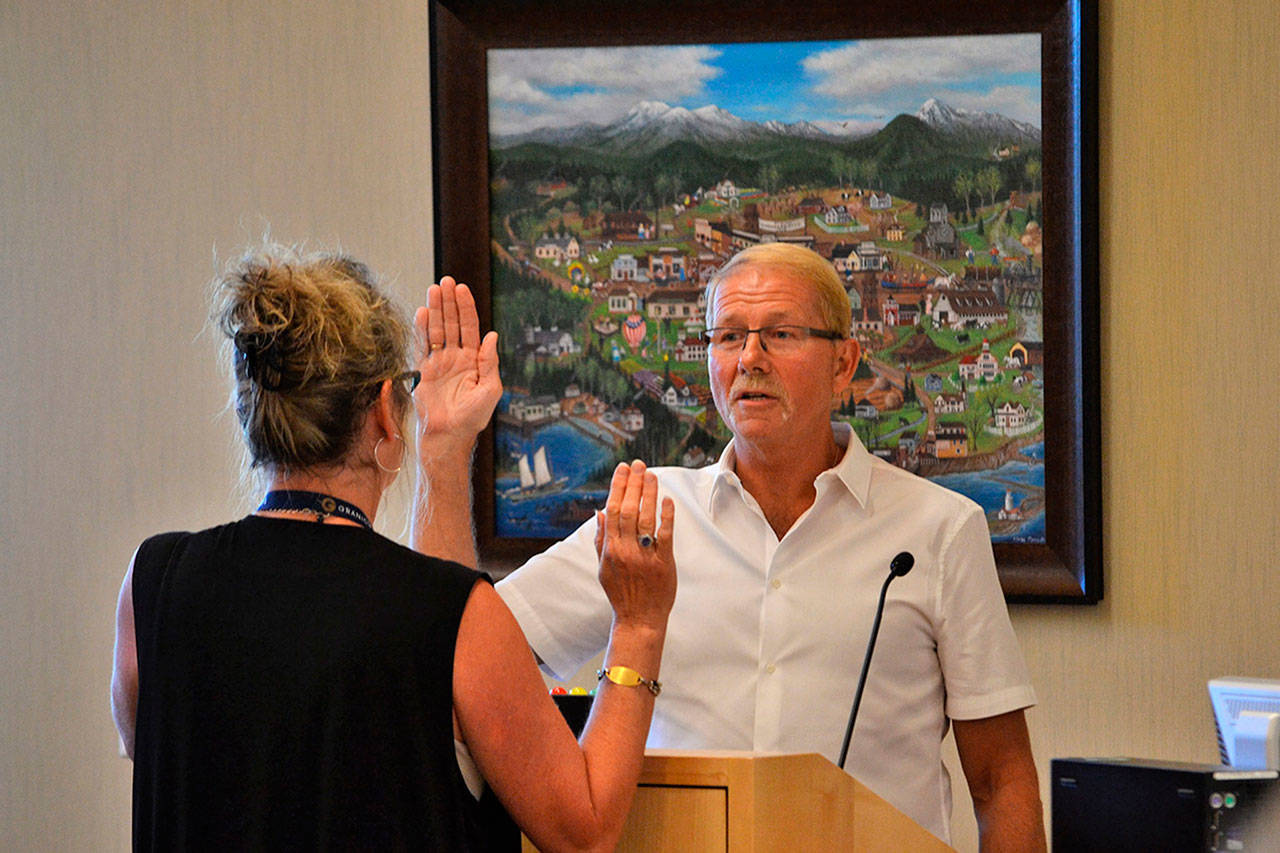 Sequim City Clerk Karen Kuznek-Reese swears in new city council member William Armacost, 63, on Monday, after he was appointed by the City Council to fill the vacant seat of Pam Leonard-Ray, who resigned in May. (Matthew Nash/Olympic Peninsula News Group)