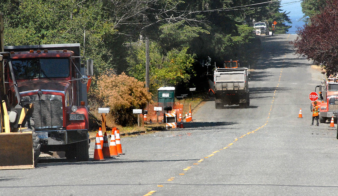 A dump truck makes its way through a construction zone as flaggers control traffic along West 10th Street in Port Angeles on Wednesday. (Keith Thorpe/Peninsula Daily News)