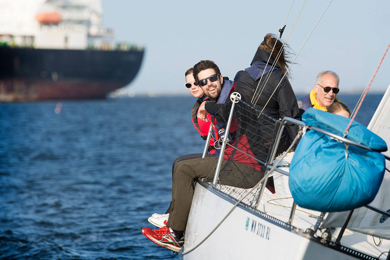 Crew members of the Wild Thing hang over the side of their boat during the Port Angeles Yacht Clubs beer can races in the Port Angeles Harbor on Friday. (Jesse Major/Peninsula Daily News)