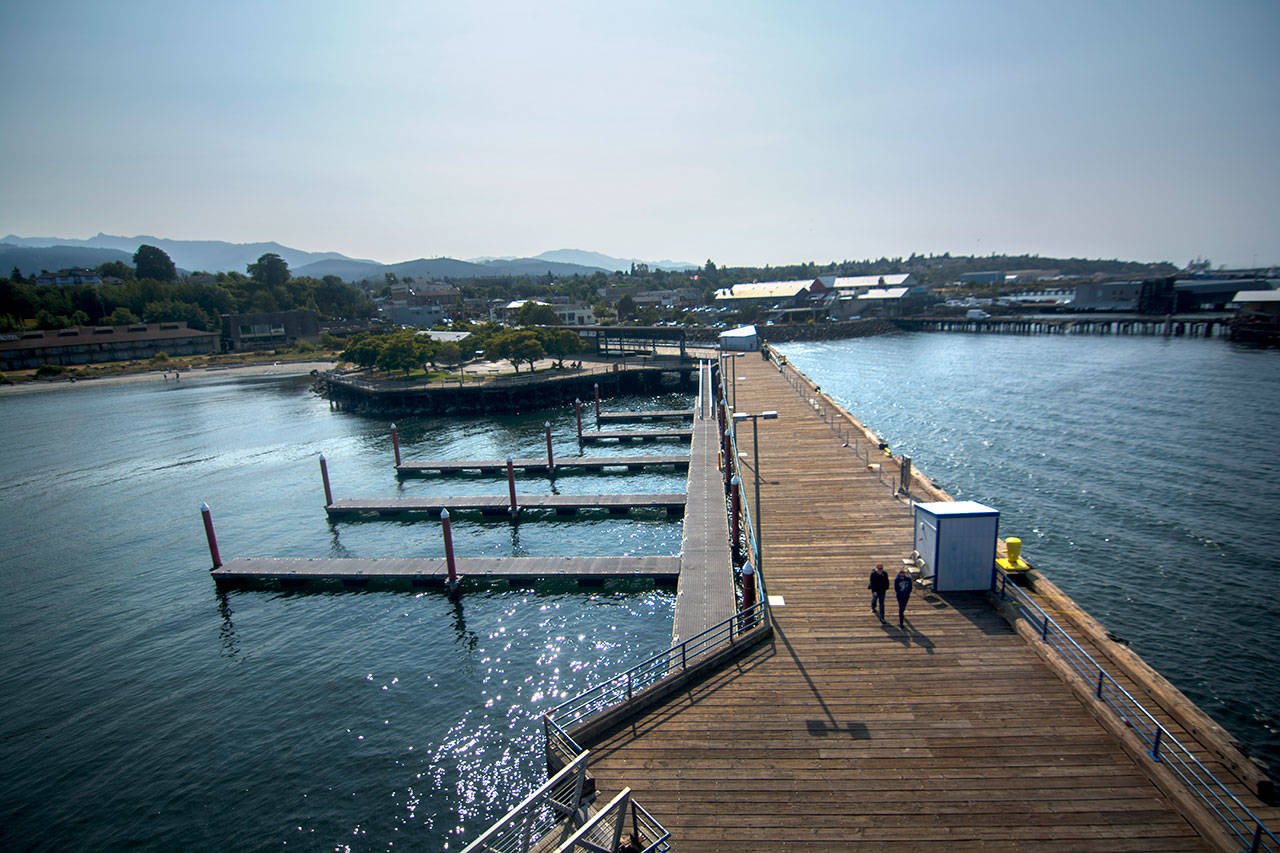 People walk on the Port Angeles City Pier on Monday. A report released Monday predicts sea level rise of 1.5 feet to 3 feet in the Pacific Northwest by 2100. (Jesse Major/Peninsula Daily News)