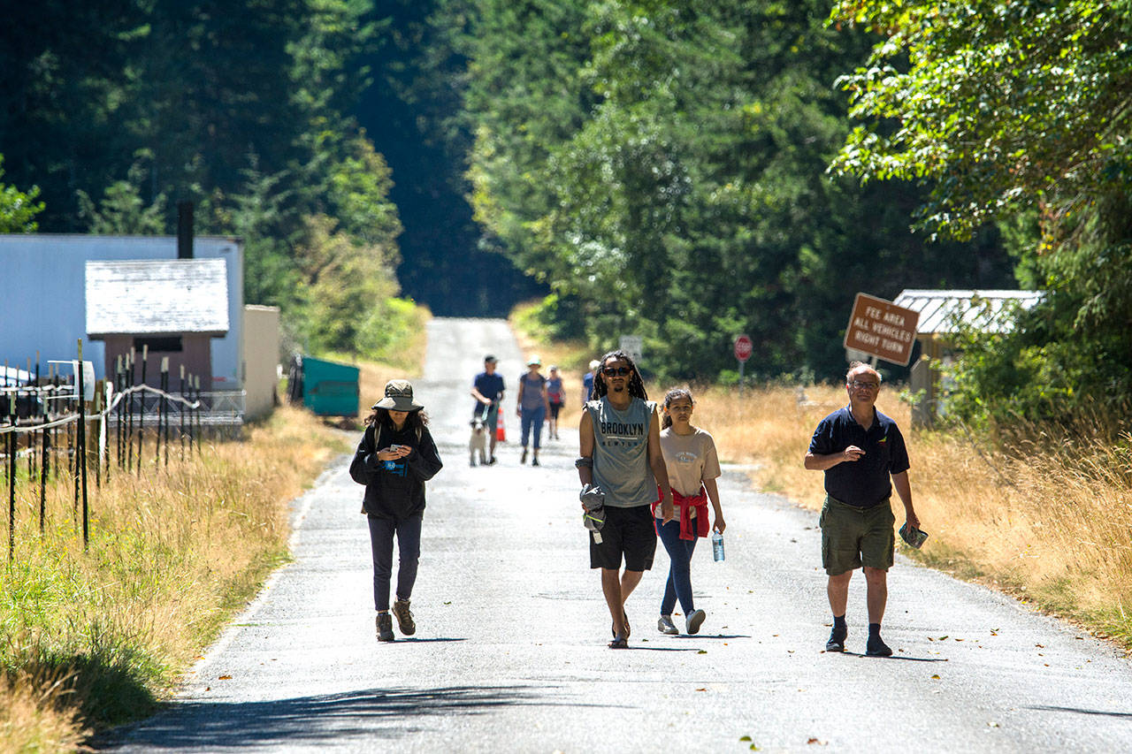 On Sunday, visitors to Olympic National Park walk along Olympic Hot Springs Road, which has been closed to vehicle traffic after winters storms washed out the road near the former Elwha Campground. Olympic National Park is seeking public comment on its proposal to investigate whether it is feasible to move the road out of the river’s flood plain. (Jesse Major/Peninsula Daily News)