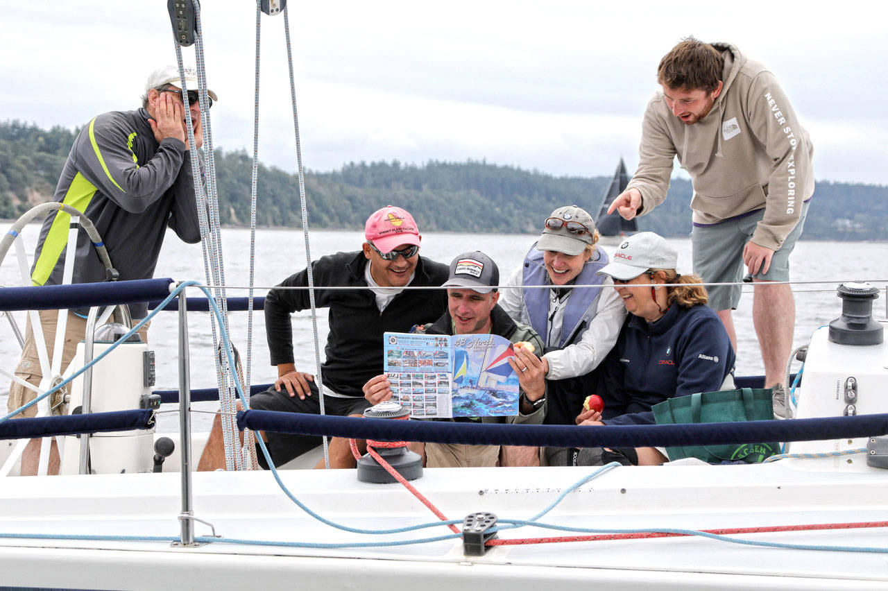 The crew of Moose Unknown reads the latest issue of 48°North — a magazine dedicated to sailing in Washington, Oregon, Alaska and British Columbia — during Whidbey Island Race Week in July. (Jan Anderson)