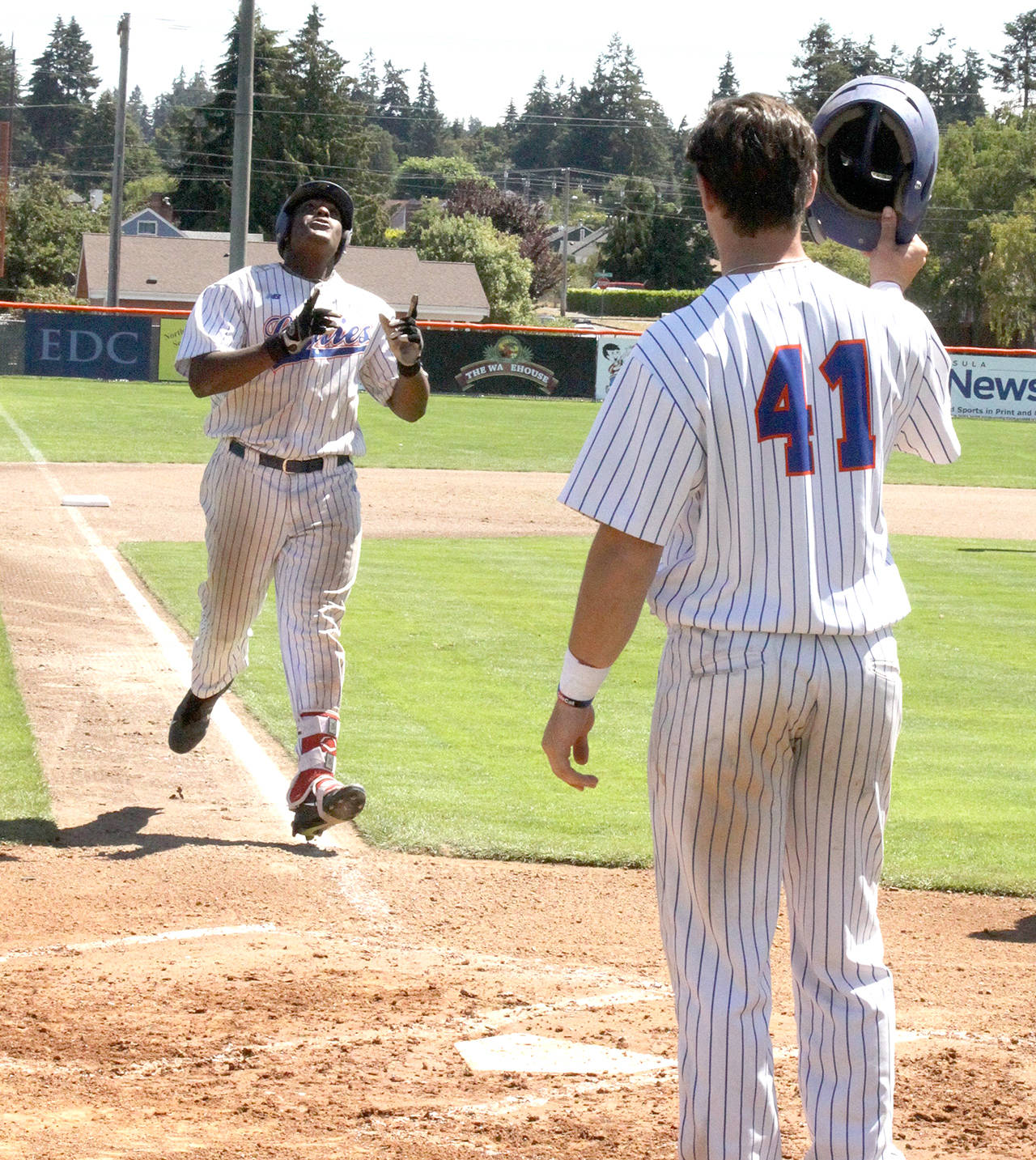 Dave Logan/for Peninsula Daily News Port Angeles’ Ron Brown, left, points to the heavens as teammate Trey Morgan waits to congratulate the Houston slugger on his sixth home run of the season.