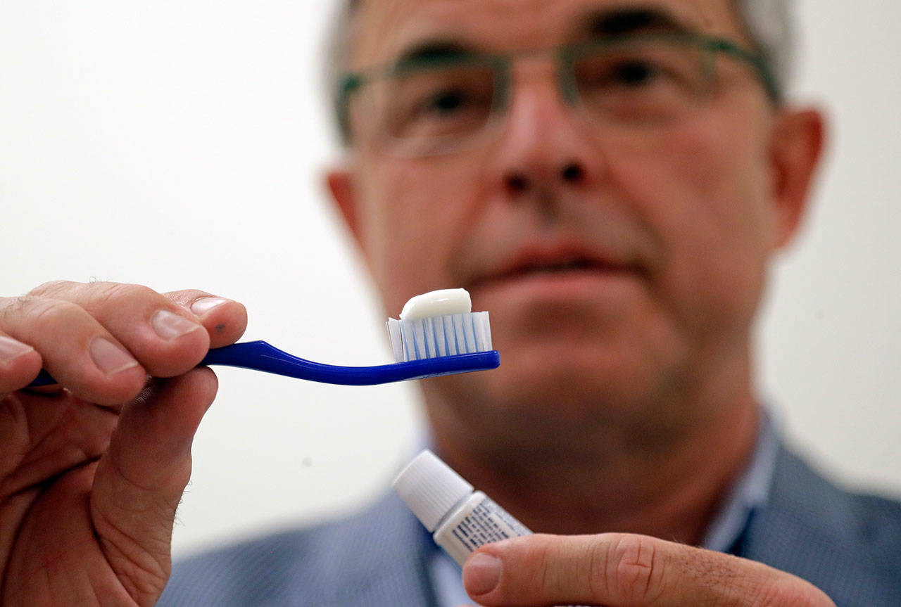 Philippe Hujoel, a dentist and University of Washington professor, holds a toothbrush and toothpaste as he poses for a photo in an office at the school in Seattle. (Elaine Thompson/The Associated Press)