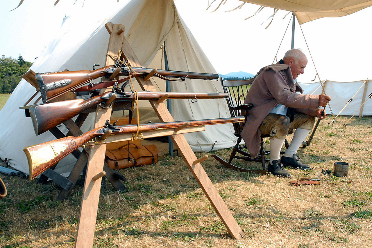 Colonial reenactor Bill Sick of Yelm cleans a replica of an musket rifle near a display of weapons modled from the era. (Keith Thorpe/Peninsula Daily News)