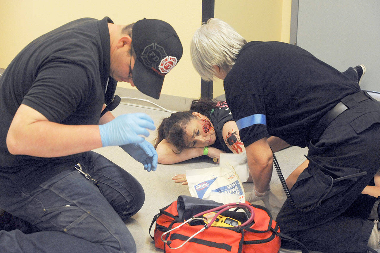 Medics attend to a person playing an injured patient in a hallway of the Clallam Bay High School. (Lonnie Archbald/for Peninsula Daily News)