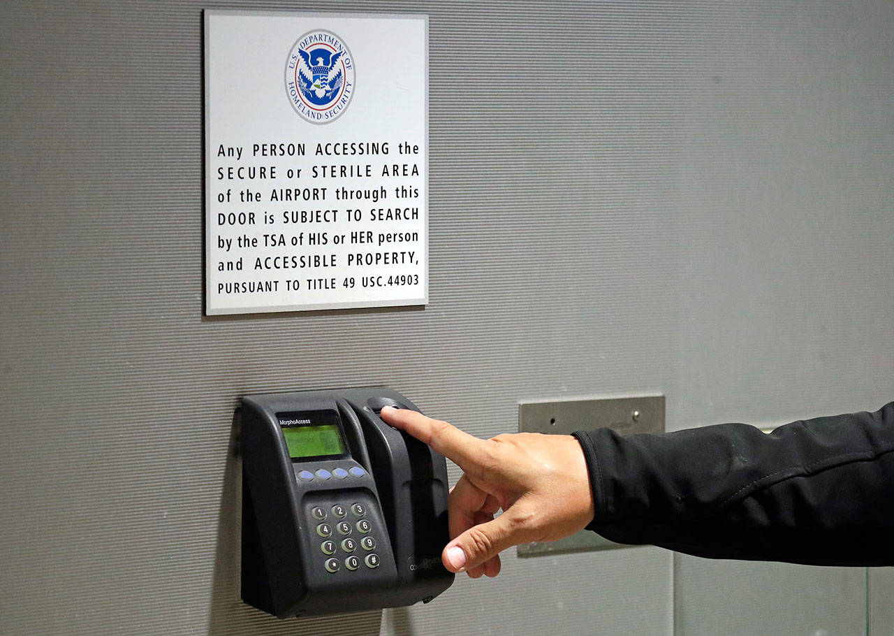 A worker at Seattle-Tacoma International Airport places his finger on a biometric screening device before entering a secured area of the airport Monday. (Elaine Thompson/The Associated Press)