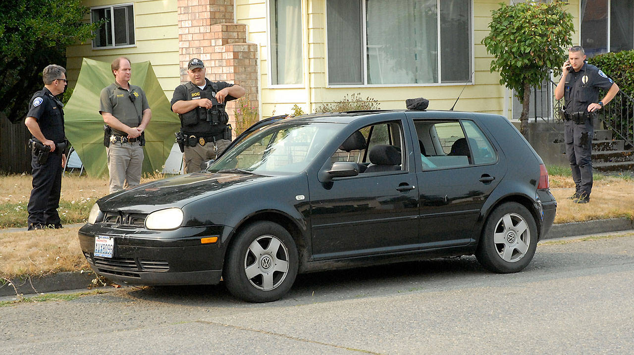 Law enforcement officers gather around car involved in a police pursuit around Port Angeles that involved striking a state Department of Corrections officer and the eventual felony arrest of the driver in the 300 block of South Cherry Street in Port Angeles on Tuesday. (Keith Thorpe/Peninsula Daily News)