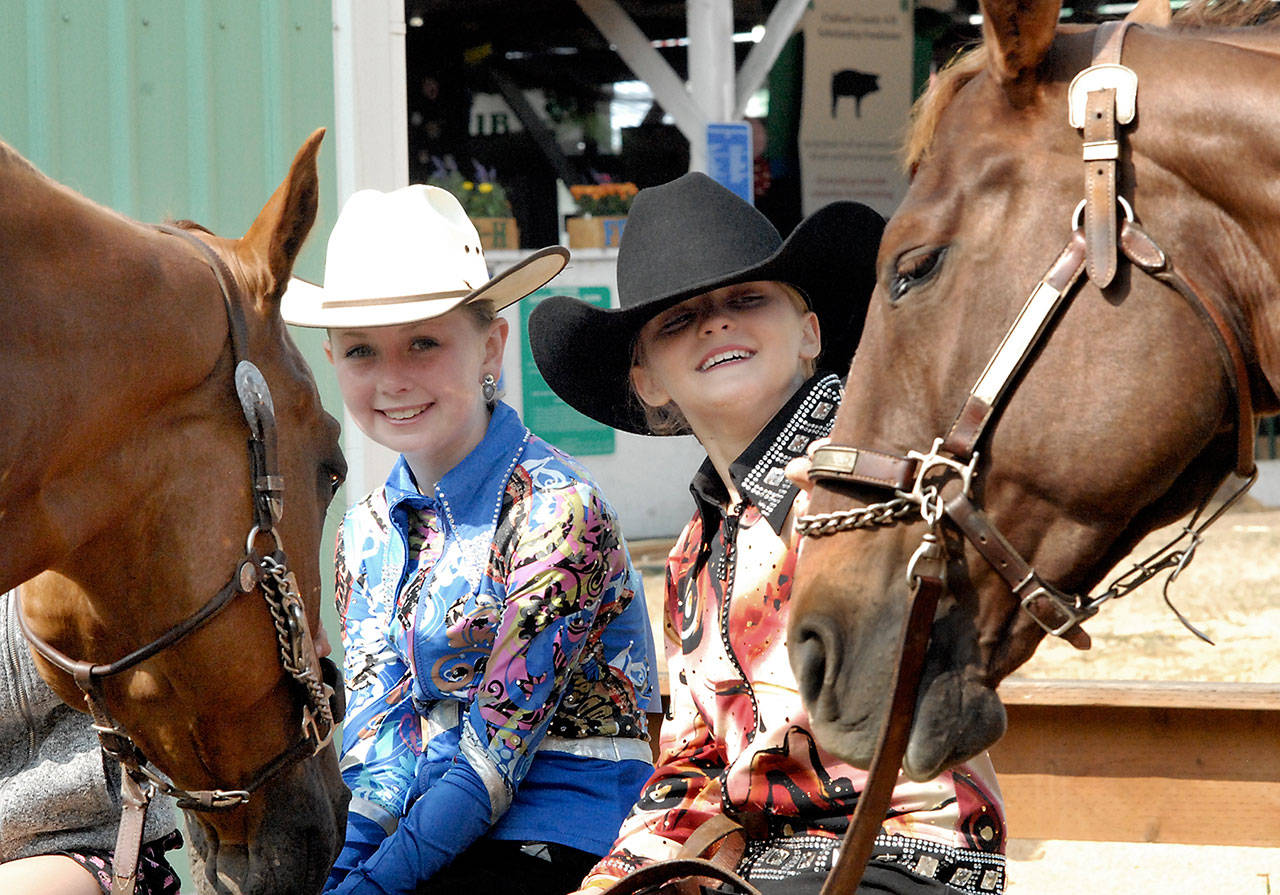 Lillian Bond, 9, and her horse, Mac, left, and Kennady Gilbertson, 11, and her horse, Copper, sit outside a horse barn at the Clallam County Fair on Thursday. The girls, both of Port Angeles and members of the Pony Express 4-H Club, were waiting for their turn before the judges in the show ring. (Keith Thorpe/Peninsula Daily News)