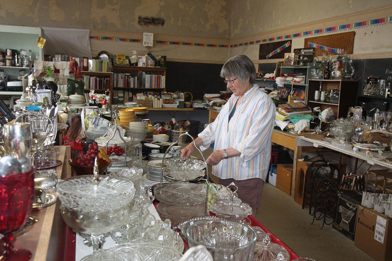 Kathy Estes, executive director of the Clallam County Historical Society, adjusts an item that is among those to be sold in the 24th annual garage sale. (Dave Logan/for Peninsula Daily News)