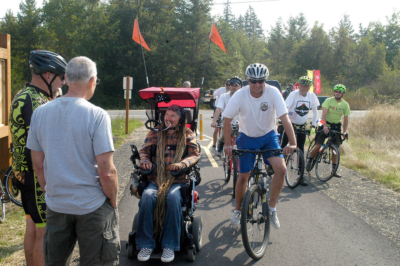 Ian Mackay and his supporters stop to celebrate after crossing the Clallam-Jefferson County line on the Olympic Discovery Trail at Diamond Point Road on Friday. Mackay had traveled on his wheelchair from Coeur d’Alene, Idaho to highlight the need for wheelchair-accessible trails in Washington. (Rob Ollikainen/Peninsula Daily News)