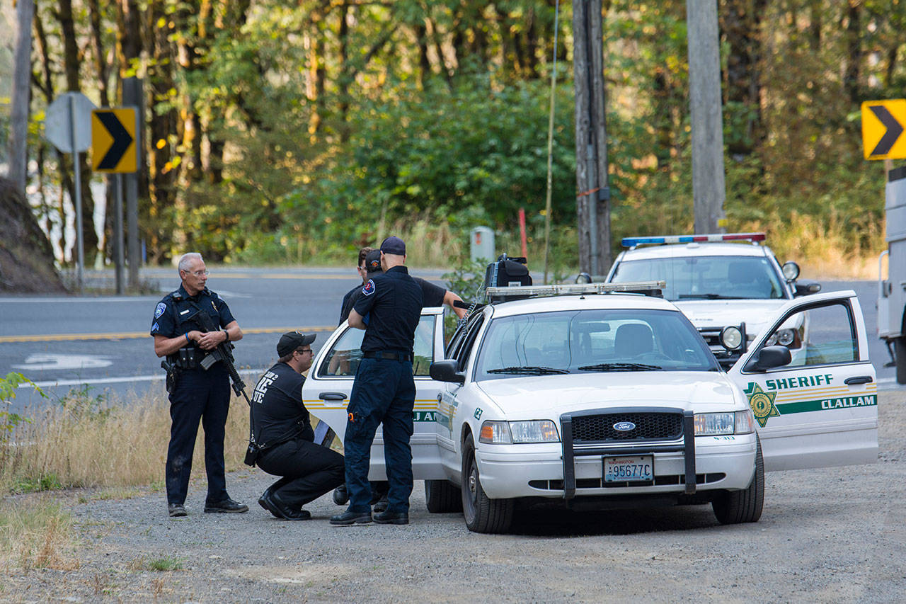 Police and paramedics talk to Robertson L. Walker, 23, Tuesday morning. Police say Walker led law enforcement on a pursuit that ended with the vehicle he was driving rolling down the bank of the Elwha River. (Jesse Major/Peninsula Daily News)